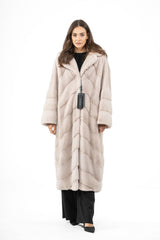 Powder-toned mink fur coat featuring a V-chevron pattern on the body and horizontal panels on the sleeves, with a notch collar and long fit.