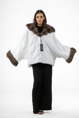White mink fur jacket featuring a brown fur hood and wide cuffs. The body has horizontal piecing arranged in a downward-pointing V chevron pattern.