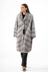 Light grey sapphire mink jacket with a notched collar, featuring fur worked into a V-chevron pattern on the body and sleeves, mid-thigh length.