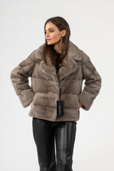 Silver blue mink short jacket with horizontal fur panels, notched collar, and full sleeves. Worn over black leather pants with hand-in-pocket pose.