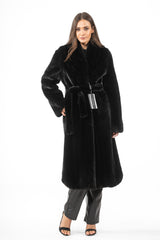 A knee-length black mink fur coat with a plush texture, featuring a wide shawl collar, long sleeves, and a matching tie belt at the waist.