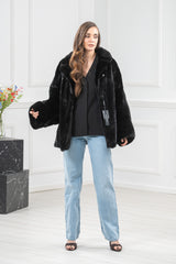 A black short mink jacket featuring wide, flared sleeves and a wide collar, styled with blue jeans.