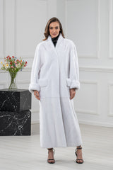 Full-length white mink fur coat with a soft shawl collar, featuring long sleeves with wide turned-up cuffs and horizontal side pockets.