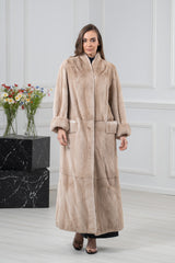 A floor-length Palomino mink fur coat featuring a soft beige tone, wide collar, and large cuffs. The design includes horizontal panels at the hem.