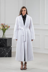 Full-length white mink fur coat featuring a wide shawl collar, long sleeves, and a matching tie-waist belt over a black outfit.