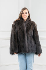 Natural fisher fur jacket with a dark brown, multi-tonal pile, wide sleeves, and a prominent stand-up collar, worn over light blue denim jeans.
