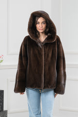 Mahogany mink fur short jacket with a hood, featuring wide sleeves and a drawstring hem with metallic toggles, displayed on a woman.