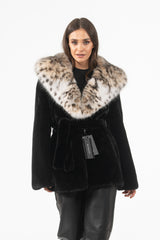 Short black mink fur jacket featuring a large, spotted lynx fur collar and hood, with a matching black fur tie-belt at the waist.