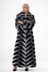Long chinchilla coat with a V-chevron pattern in grey, black, and white tones, featuring a wide collar and long sleeves.