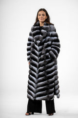 Long chinchilla fur coat in gray and black with a V-chevron pattern, featuring a wide folded collar, long sleeves, and a full-length fit.