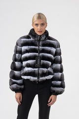 Front view of a natural chinchilla fur jacket with a high collar and horizontal dark grey and white panels, featuring a full-length front zipper.