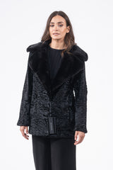 Black Swakara skin short jacket featuring a wide collar with long-hair fur trim and a wavy, textured fur body, worn over a black sweater.