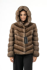Short Russian sable jacket in brown with a large hood and a directional V-chevron pattern, shown from the front with a hanging brand tag.