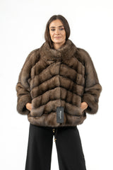 A short Russian sable jacket with a soft brown hue and a V-chevron pattern. It features a wide collar, cropped length, and long sleeves.