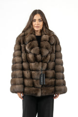 Short Russian sable jacket in brown, featuring a horizontal panel construction, a wide collar, and straight sleeves worn over black trousers.