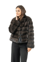 Short Russian sable jacket in a dark carbonio shade, featuring horizontal fur panels and a standing collar, worn by a woman facing forward.