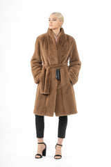 Front view of a brown mink fur jacket with a shawl collar, belted waist, and below-the-hip length, worn over black pants and heels.