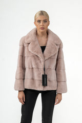 Salmon mink fur jacket with horizontal panels, a wide collar, and a straight cut. The light pink fur has a uniform, dense texture.