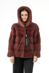 Aged wine mink fur jacket with a deep hood, featuring horizontal panel construction, a front hook closure, and a brand tag at the neckline.
