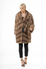 Short pastel mink fur jacket with a notched collar, featuring a chevron V-pattern on the body and wide, horizontal panel sleeves.