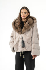 Short powder-colored mink fur jacket featuring a brown fur-lined hood, a V chevron pattern, and horizontal panels on the sleeves.