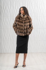 A short Russian sable jacket with horizontal fur panels, a round collar, and a smooth, fitted silhouette worn over a black dress.