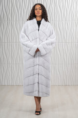 Full-length white mink fur coat featuring a chevron V-pattern on the torso and horizontal fur panels on the sleeves.