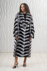 A knee-length natural chinchilla fur coat featuring a V-chevron pattern, a notched collar, and a straight silhouette.