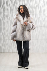 Short fawn light fox fur jacket with a wide lapel collar, long sleeves, and a vertical construction on the body, worn over black trousers.