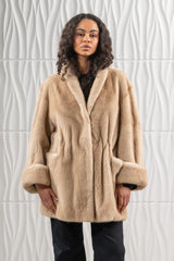 Palomino mink short jacket with a wide shawl collar, dropped shoulders, and deep turn-up cuffs. Features a cinched waist and front slip pockets.