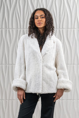 White mink fur short jacket with a curly texture, featuring a wide lapel collar, long sleeves with folded cuffs, and a drawstring hem.