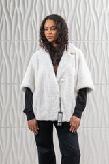 Short white teddy bear mink fur jacket with a wide lapel, loose elbow-length sleeves, and a single large button closure at the waist.