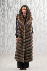 Floor-length Russian sable vest in brown, featuring a front V chevron pattern and a wide collar, worn over a black shirt and trousers.