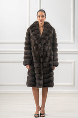 Knee-length Russian sable jacket in dark brown with a wide collar and horizontal banded fur construction, worn open by a model.