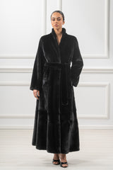 Full-length black mink fur coat with a stand collar, long sleeves, and a matching tie-waist belt. The hem features a horizontal panel design.