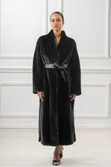 A black mink fur coat with a calf-length silhouette and wide lapels, cinched at the waist with a black leather tie belt.
