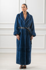 A blue mink fur coat featuring a long, straight silhouette, wide collar, and a black leather belt at the waist with folded cuffs on the sleeves.