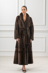 Brown mink fur coat with a wide collar, long sleeves, and a belted waist. It features a horizontal panel design at the lower hem.