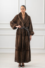 Brown mink fur coat featuring a wide shawl collar, full-length silhouette, loose sleeves with folded cuffs, and a matching brown leather waist tie.