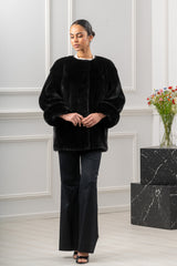 A black mink fur jacket for women with a collarless, round neckline and wide, three-quarter length sleeves featuring deep, fold-over cuffs.