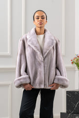 Short velvet mink fur jacket in silver blue with a wide collar and large folded cuffs, showcasing a smooth, uniform texture.