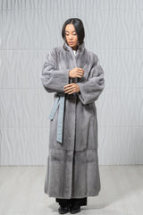 Long sapphire mink fur coat featuring a soft, velvet-like texture, a wide collar, dropped shoulders, and a matching grey leather waist tie.