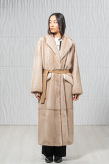 Palomino mink fur coat with a wide collar and tan suede waist tie. The design features horizontal panels and a soft, uniform fur texture.