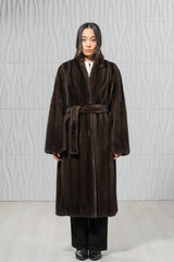 Dark brown mink fur coat with a matching tie belt, long sleeves, and a simple collarless silhouette, shown tied at the waist.