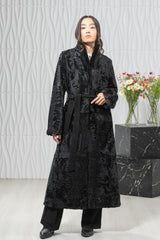 A black Swakara long-hair coat with a waist-cinching belt, featuring a classic straight silhouette, stand collar, and flat fur texture.