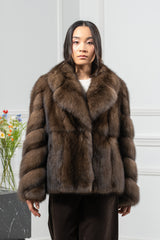 Short brown Russian sable jacket with a wide collar and sleeves featuring a V-chevron pattern, worn open over dark trousers.
