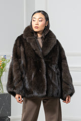 A short Russian sable jacket in dark brown, featuring a wide shawl collar, wide sleeves, and a vertical pelt construction, worn over a brown outfit.