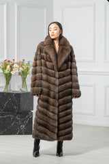 A brown Russian sable coat with a V chevron pattern, wide notched collar, and long sleeves, shown from the front on a model in black heels.