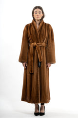 Gold mink fur coat with a vertical pelt pattern, shawl collar, and matching fur tie belt. The full-length design features long, straight sleeves.