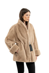 A Palomino mink fur jacket in a light tan shade. It features a standing collar, wide cuffed sleeves, and a cinched waist with a tie closure.